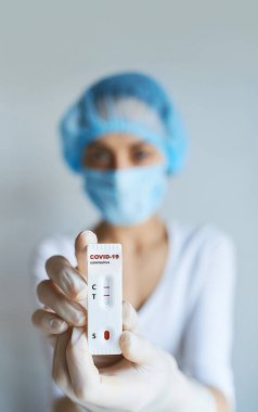 Doktor ya da bilim adamı yüz maskesi ve eldiven giymiş laboratuvarda viral hastalık COVID-19 için laboratuar kartı testi yapıyorlar. Test pozitif sonuç veriyor. Koronavirüs teşhisi, salgın hastalıkların önlenmesi.