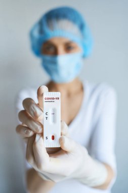 Doktor ya da bilim adamı yüz maskesi ve eldiven giymiş laboratuvarda viral hastalık COVID-19 için laboratuar kartı testi yapıyorlar. Test negatif sonuç veriyor. Koronavirüs teşhisi, salgın hastalıkların önlenmesi.