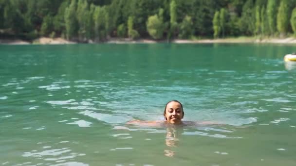 Bela mulher feliz esbelta em roupa de banho azul sai do lago da montanha depois de nadar — Vídeo de Stock