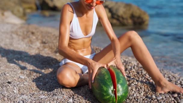 Tanned slim fitbody joyful woman hands breaking huge ripe watermelon into two halves. — Stock Video