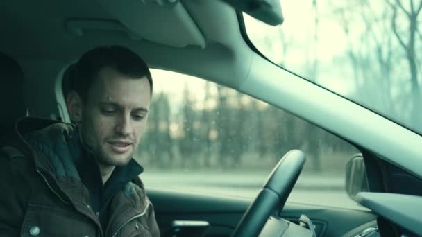 Чоловік водій в автомобільній кабіні за допомогою телефону — стокове відео