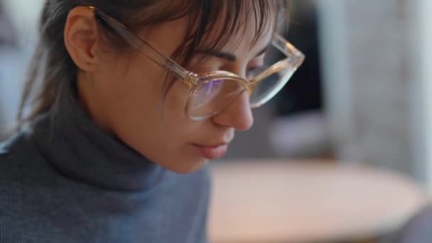 Primer plano retrato morena mujer en gafas y suéter gris trabajando por ordenador portátil — Vídeos de Stock