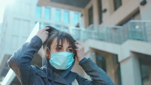 Gemengd ras brunette vrouw in hoodie uit en over in de stad straten dragen gezichtsmasker — Stockvideo