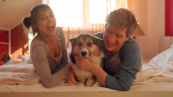 Happy family lying with dog on bed at home — Stock Video