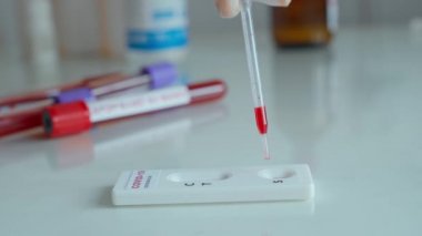 Eldivenli doktor viral hastalıklar için hızlı test yapıyor. Laboratuvar kâğıdına kan damlatıyor.