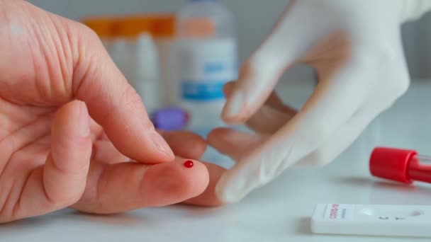 Arts in het ziekenhuis die bloeddruppels uit een vinger van een patiënt neemt — Stockvideo