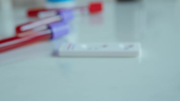 Mãos médico close-up colocar em tubo de teste de mesa com amostra de sangue para análise COVID-19 — Vídeo de Stock