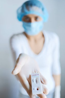 Doktor ya da maskeli hemşire viral hastalık COVID-19 için laboratuvar kartıyla kamera karşısına geçiyor. Test pozitif sonuç gösteriyor.