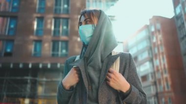 Viral enfeksiyonu önlemek için kapüşonlu ve koruyucu maskeli bir kadın.