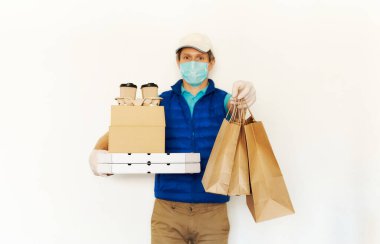 Karantina sırasında teslimat. Koruyucu maskeli kurye ve karton kutular taşıyan eldivenler paket yemek için kağıt torbalara uzanıyor.