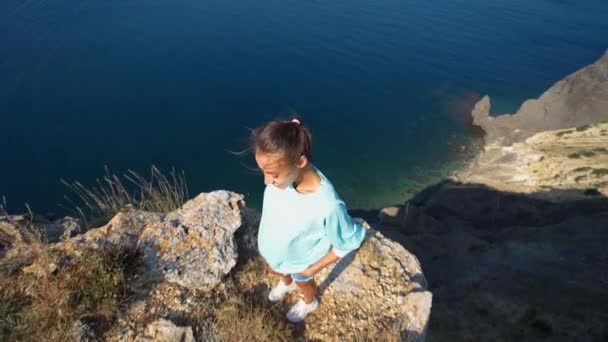 Vista superior jovem sorrindo mulher feliz em pé na borda alta do penhasco sobre o mar — Vídeo de Stock