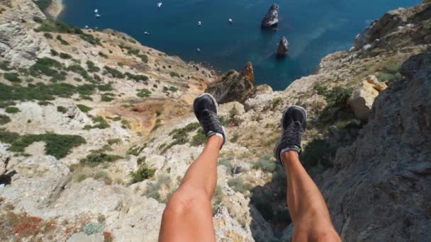 POV primeira pessoa ver pernas masculinas em shorts sentado na borda do penhasco com vista incrível — Vídeo de Stock