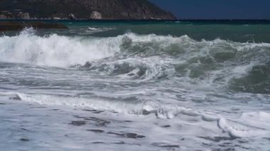 Çakıl taşlı deniz sahilinde ağır çekim dalgaları.