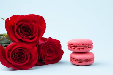 Kırmızı Güller ve Fransız Macaronlu Sevgililer Günü Kavram Kartı. Arka plan Pastel Mavi Sanat Kağıdı. Kapat..  