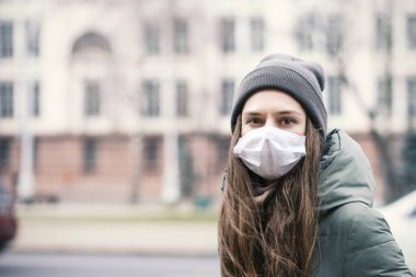 Şehir Caddesindeki koruyucu maskeli genç kız. Konsept - Virüs enfeksiyonunu önlemek. Avrupa. Kasaba. Sıradan. Kapatın. Seçici Odaklanma.