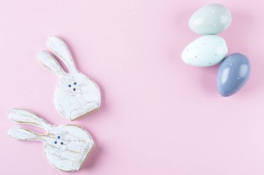Dekoratif Paskalya Yumurtaları ve İzole Pembe Arkaplanda İki Komik Tahta Tavşan. Kavram - Metin için Boşluğu Kopyalayan Paskalya Kartı. Düz Yatay.