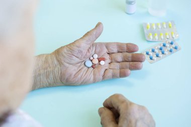 Grip belirtileri gösteren yaşlı beyaz kadın, ev karantinası. Elinde çok renkli haplar tutuyormuş. Konsept - Yaşlılar için tehlikeli virüs, kendini izole etme. Seçici Odaklanma