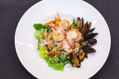 Karides, midye, kızarmış sebze, kapari, parmesan peyniri, Fransız hardallı Akdeniz salatası. Beyaz tabakta. Yaklaş.