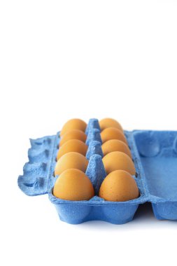 Beyaz arka planda klasik mavi bir kutuda taze çiftlik tavuğu yumurtası. Kavram - sağlıklı ve lezzetli yemek. Dikey. Seçici Odaklanma. Boşluğu kopyala. 
