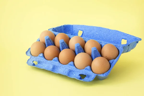 Huevos de pollo en caja de cartón azul fondo amarillo aislado . — Foto de Stock