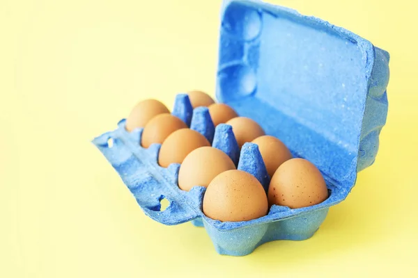 Huevos de pollo en caja de cartón azul fondo amarillo aislado . — Foto de Stock