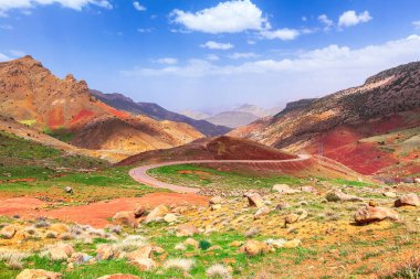 Dağların arasında dolambaçlı bir yol. Güneşli bir gün, bulutlu mavi bir gökyüzü. Renkli dağ manzarası. Fas 'ta. Panorama