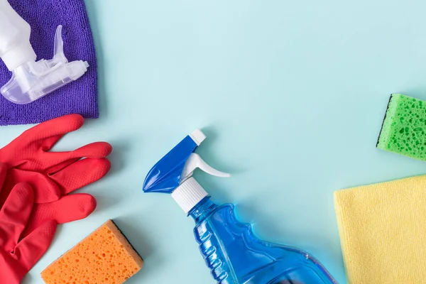 Colorful cleaning set for different surfaces in kitchen, bathroom and other rooms. Empty place for text or logo on blue background. Cleaning service concept. Top view. Flat lay.