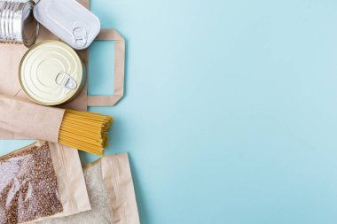 Mavi arka planda bağışçı yiyecekleri ve fotokopi alanı. Düz yatıyordu. Üst Manzara, Mock up. Pirinç, konserve yiyecek, karabuğday, reçel, makarna. Yiyecek bağışları ya da yemek servisi konsepti. Covid 19 karantinası sırasında online alışveriş