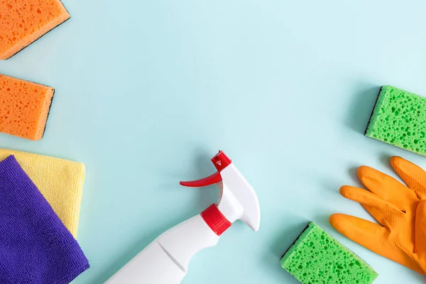 Flat lay composition. Detergents and cleaning accessories for different surfaces in kitchen, bathroom and other rooms. Empty place for text or logo on blue background. Cleaning service concept. Top view.