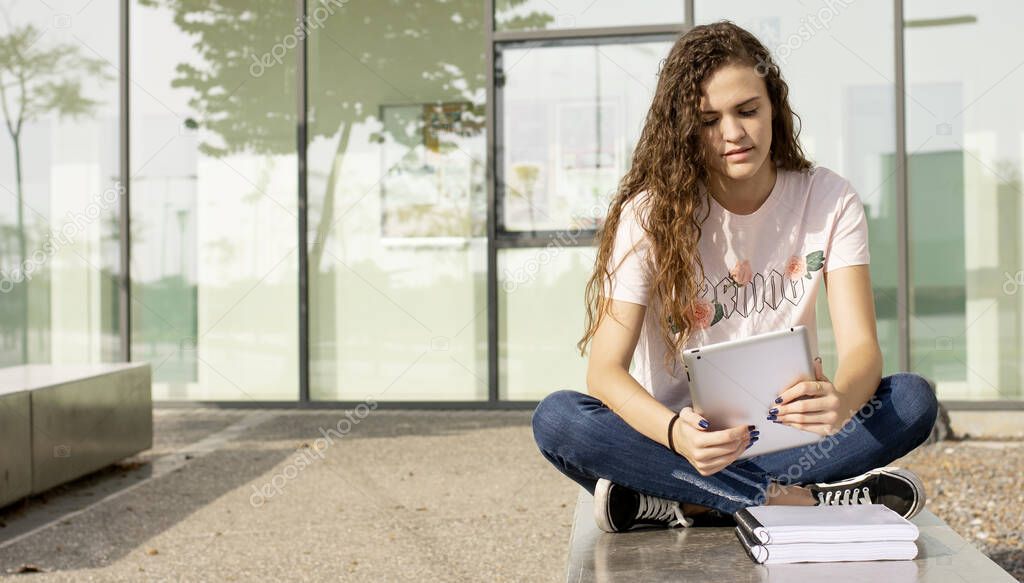 Young teenage girl at the university with books and tablet