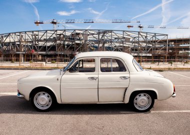 Krem rengi, mavi gökyüzü ve bulutlu klasik bir araba.