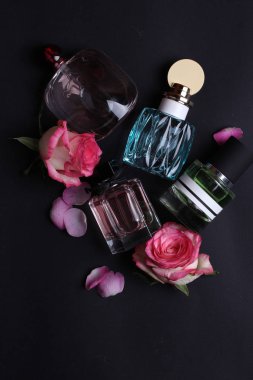 Koyu arkaplanda çiçekler olan renkli parfümler.