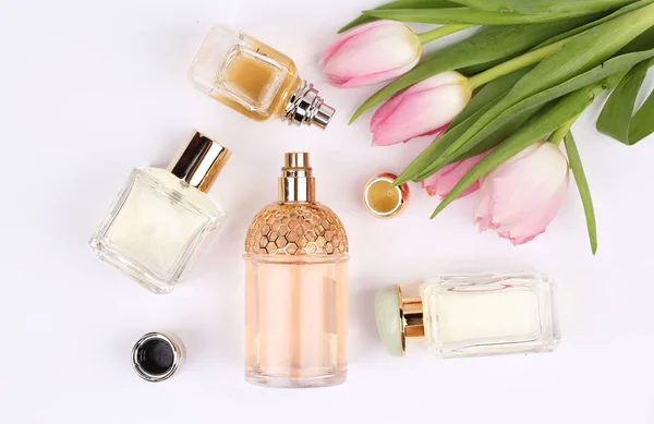 Parfumflesjes Omringd Door Bloemen Witte Achtergrond — Stockfoto