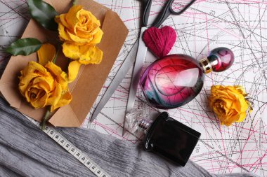 Women workplace top view, flowers, perfume, scissors, blueprints and notebook on wooden background 