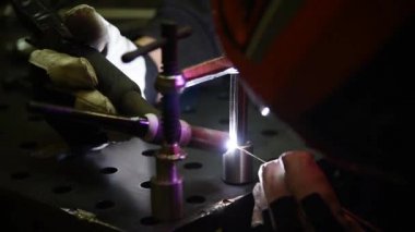 Tig kaynaklama kullanan bir kaynakçı çelik kaynak masasında çalışmak için özel klempler üretir. Bir kaynakçı metal bir alete dokunduğunda, parlak kıvılcımlar ortaya çıkar. Kavram: iş, gelenek, kaynak.