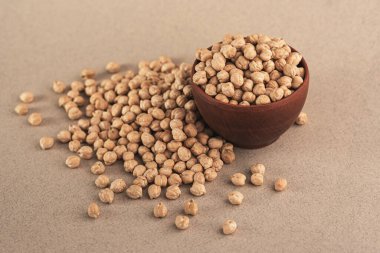 Kahverengi bir kasede çiğ nohut taneleri.