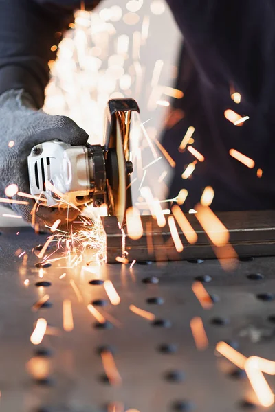 Kovový dělník řeže obdélníkovou kovovou trubku s úhlovou bruskou — Stock fotografie