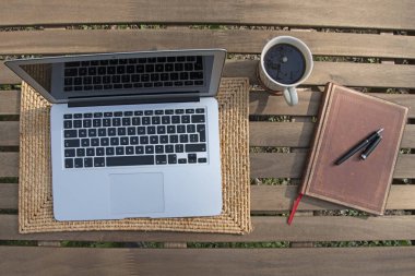 Bahçede dizüstü bilgisayar, kahve ve defter