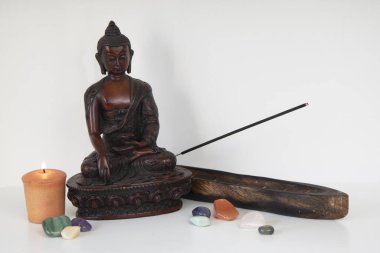 Buda heykeli, mum, tütsü ve değerli taşlar.