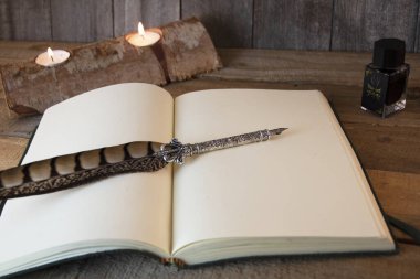 El yapımı kağıt defter, eski moda tüy kalem ve mumlar, ahşap arka plan.