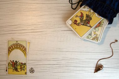 Beyaz tahta üzerinde tarot kartları, beş köşeli yıldız ve sarkacın üst görüntüsü