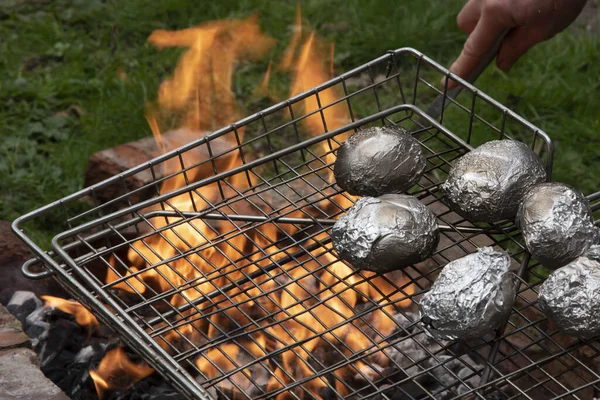 Potatoes in foil being cooked on fire, open flame