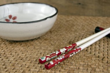 Boş beyaz kâse ve yemek çubukları, dokuma kamış arka planının minimalist sahnesi