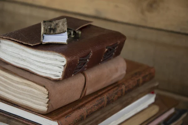 A stack of old wooden journals, with miniature wooden book on top