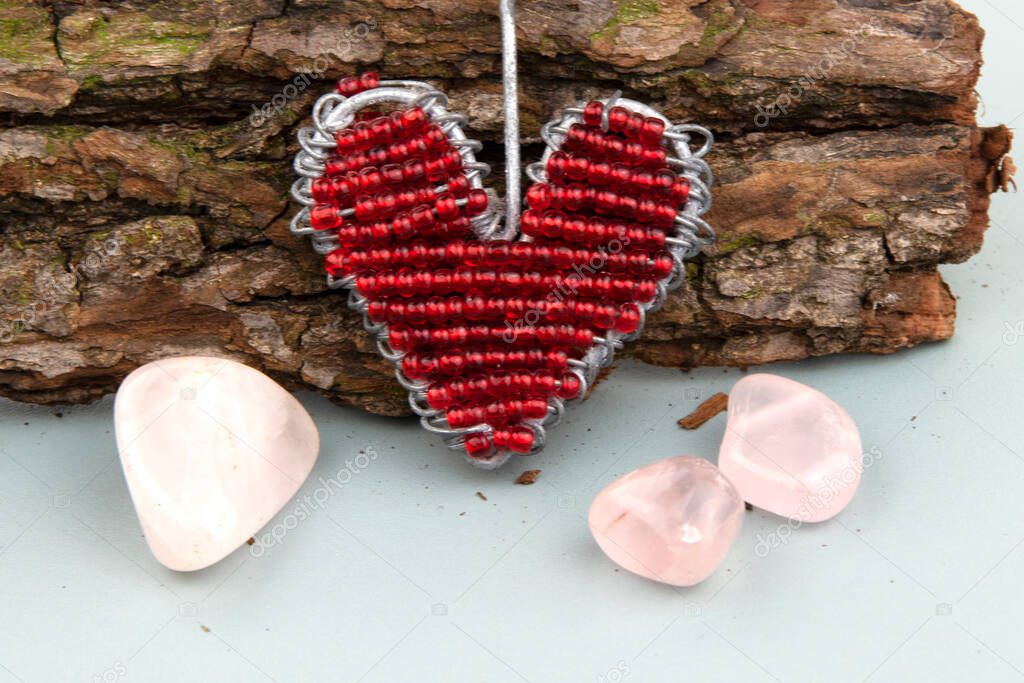 Close-up of beaded heart on rustic wooden branch with rose quartz