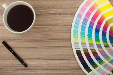 Kahve ve kalemle ahşap masanın üzerindeki renkli kartların aralığı