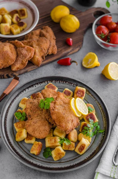 Schnitzel original with lemon and gnocchi fried — Stock Photo, Image