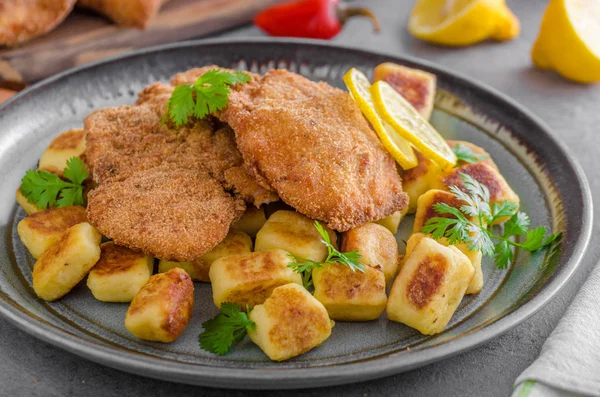 Schnitzel original with lemon and gnocchi fried — Stock Photo, Image