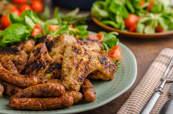 Grilled chicken wings and sausages — Stock Photo, Image