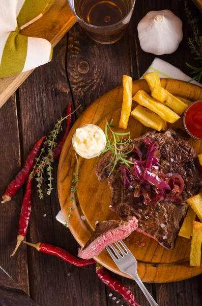 Bife com batatas fritas caseiras, cerveja e molho tártaro — Fotografia de Stock